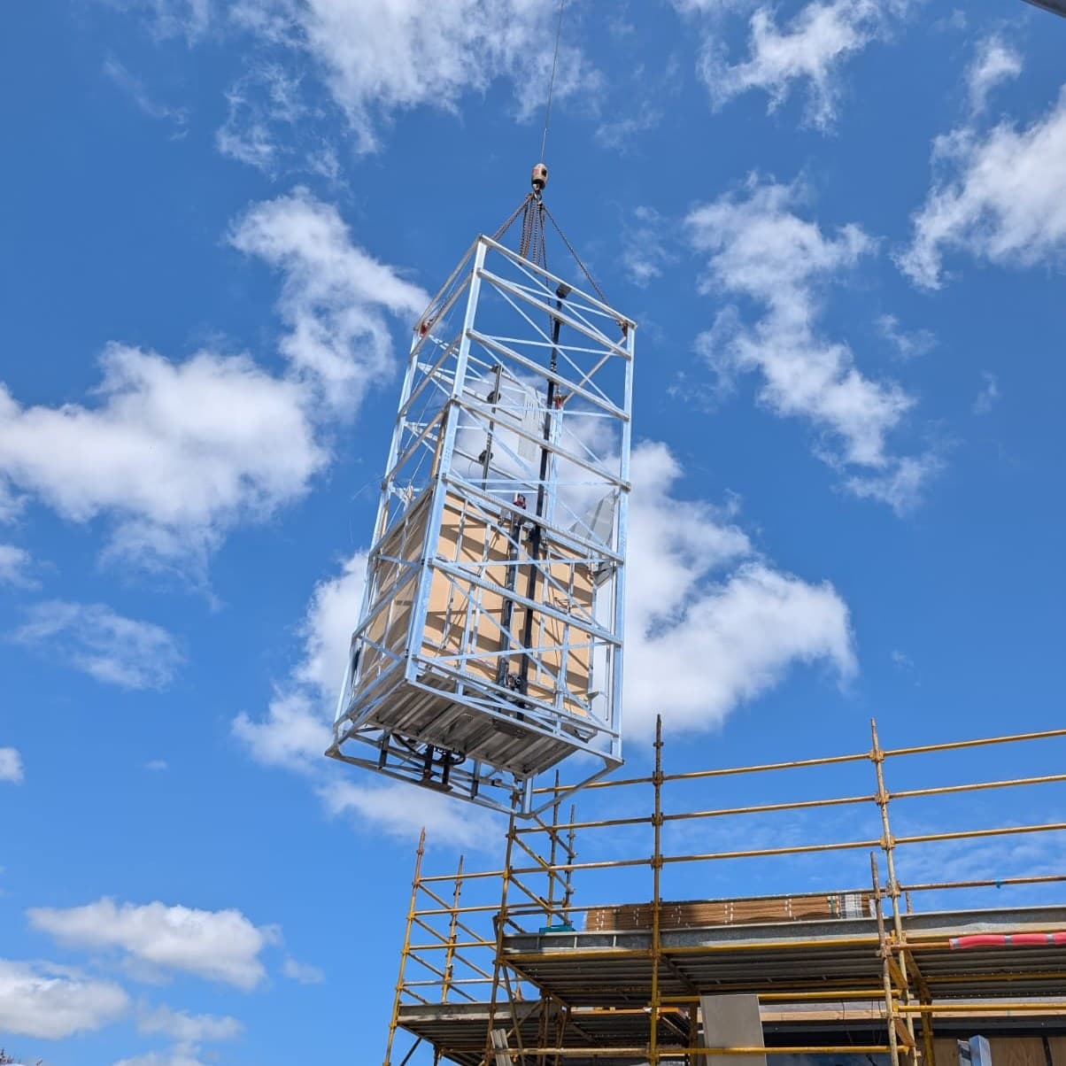 A fully assembled Southern Lifts shaft being craned into place on a construction site